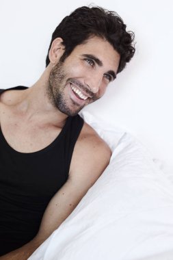 Uzağa bakarak gülen adam yatakta yeleği,