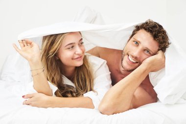 Çarşaf altında genç çift gülümseyen