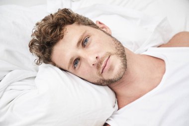 Kameraya bakarak yakışıklı adam yatakta,