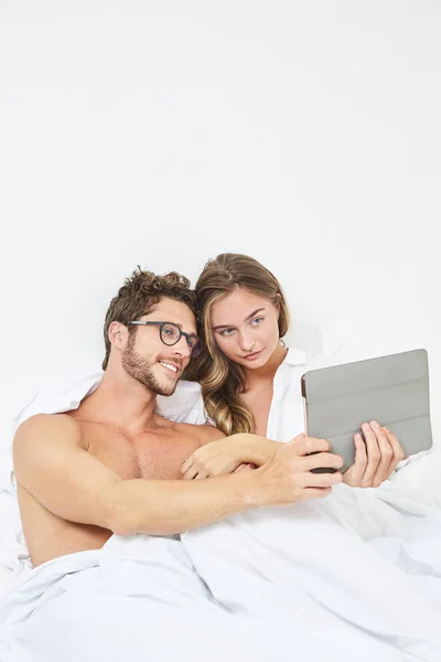 在床上使用平板电脑的年轻夫妇 — 图库照片