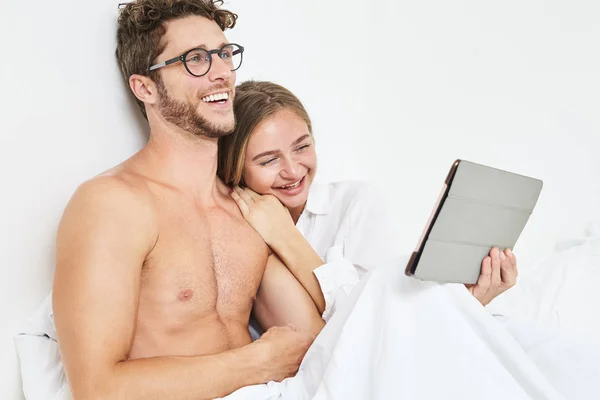 Casal Jovem Rindo Tablet Cama — Fotografia de Stock