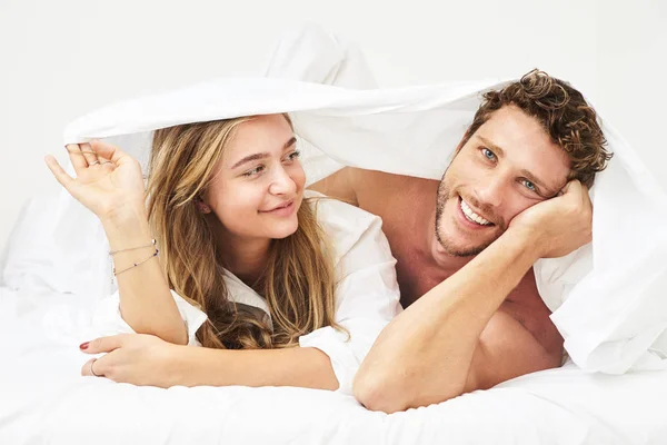 在床单下微笑的年轻夫妇 — 图库照片