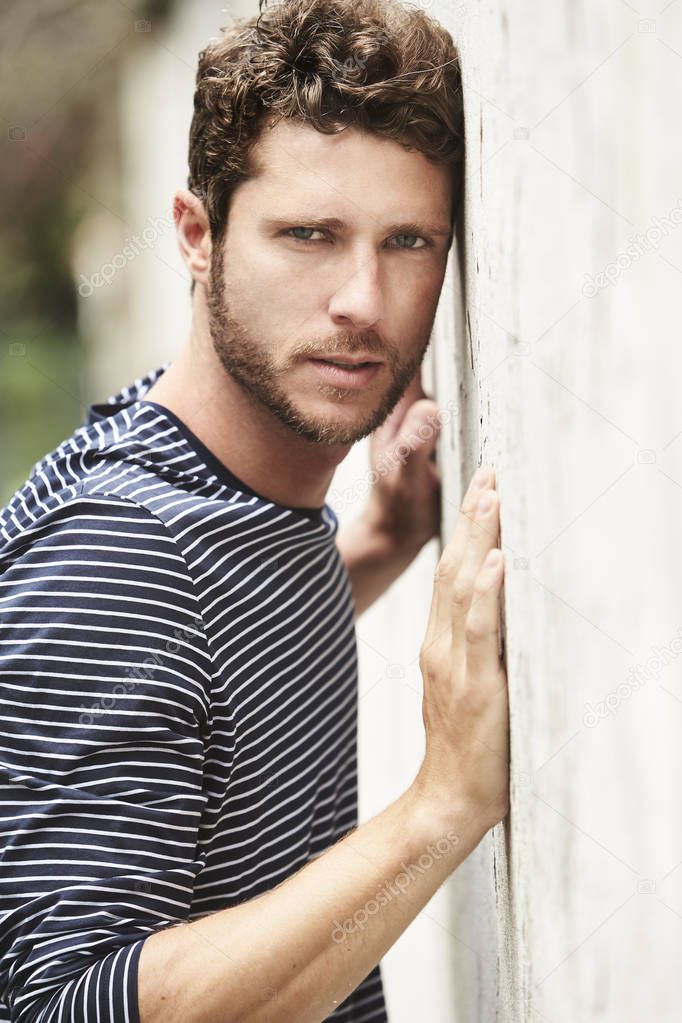 Seriously handsome hunk leaning on wall, portrait