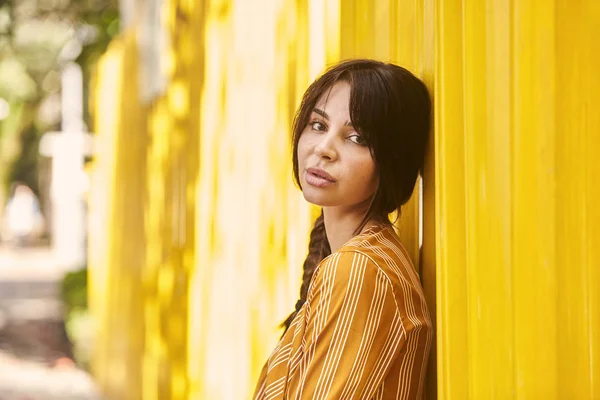 Brunette babe against yellow wall, portrait