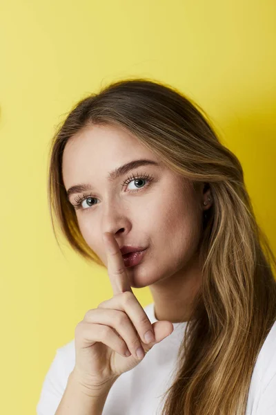 Quiet young woman with finger on lips, portrait
