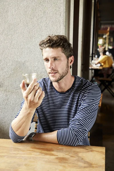 Young man looking at coffee in cafe