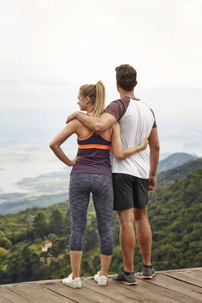 Sporty couple with arms around each other admiring view