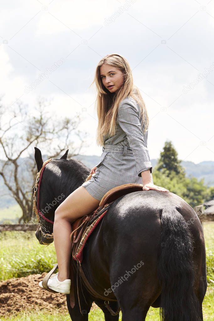 Beautiful blond woman on horse, looking over shoulder