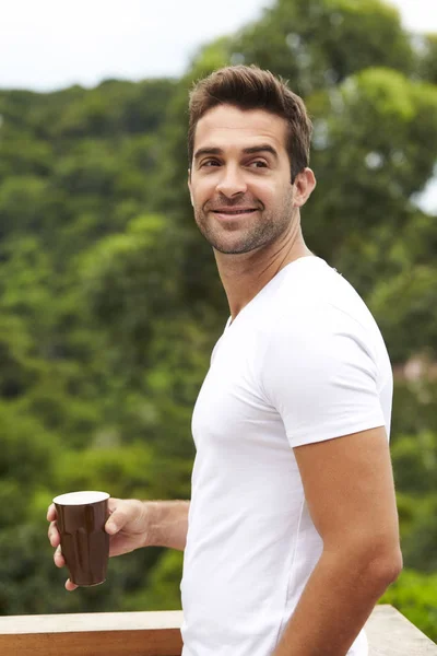 Handsome guy with coffee in white t-shirt, smiling