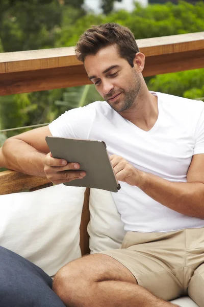 Good looking guy with tablet, relaxing on sofa