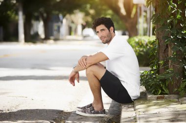 Şort ve gömlek guy kaldırım kenarında oturan