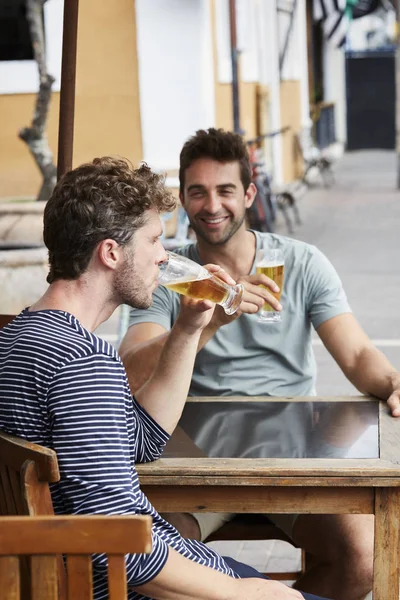 Good friends with beers at cafe, smiling