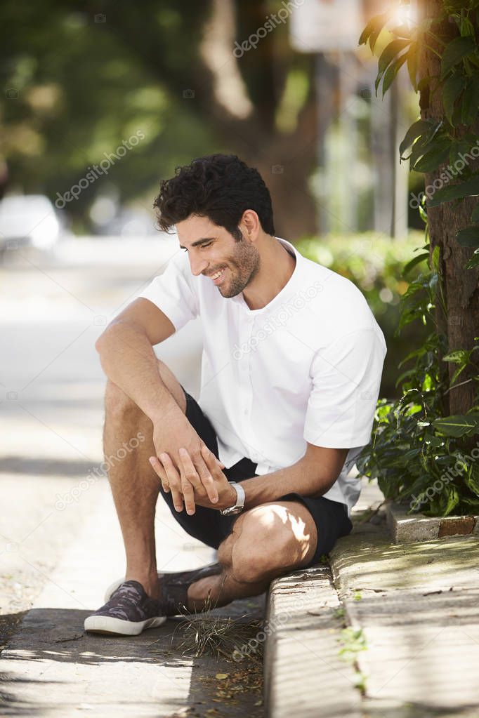 Handsome guy in shorts sitting in road