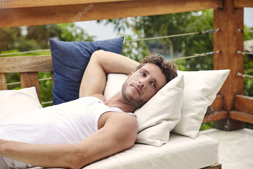 Resting young man in vest on balcony