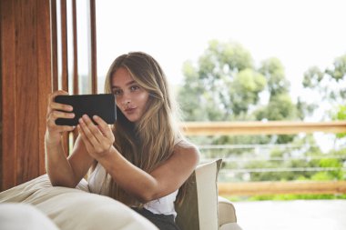 Genç güzel sarışın kadın kanepe üzerinden somurtarak selfie alarak