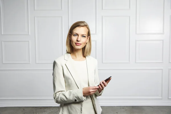 Professional businesswoman in white suit with phone, portrait