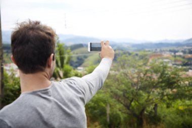 Manzara fotoğraf için akıllı telefon kullanan adam