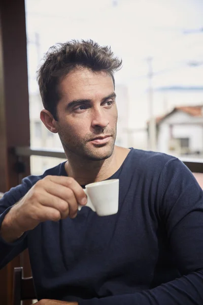 Handsome guy with coffee in cafe, looking away