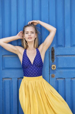 Stunning young woman in blue top and yellow culottes, portrait