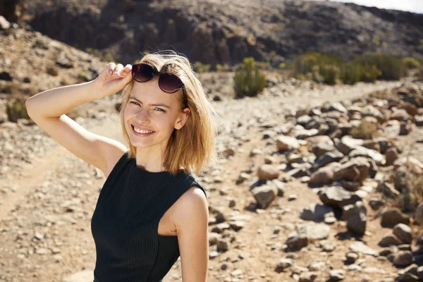 Smiling young model in desert, looking at camera