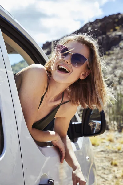 Excited young woman on road trip in car, looking away