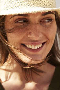 Yakın yukarı rüzgarlı saçları ile gülümseyen esmer, gülümseyen