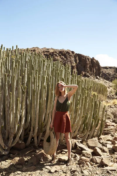 Beautiful woman standing by desert cactus, portrait