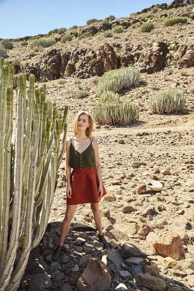 Confident girl standing by cactus in desert landscape, portrait