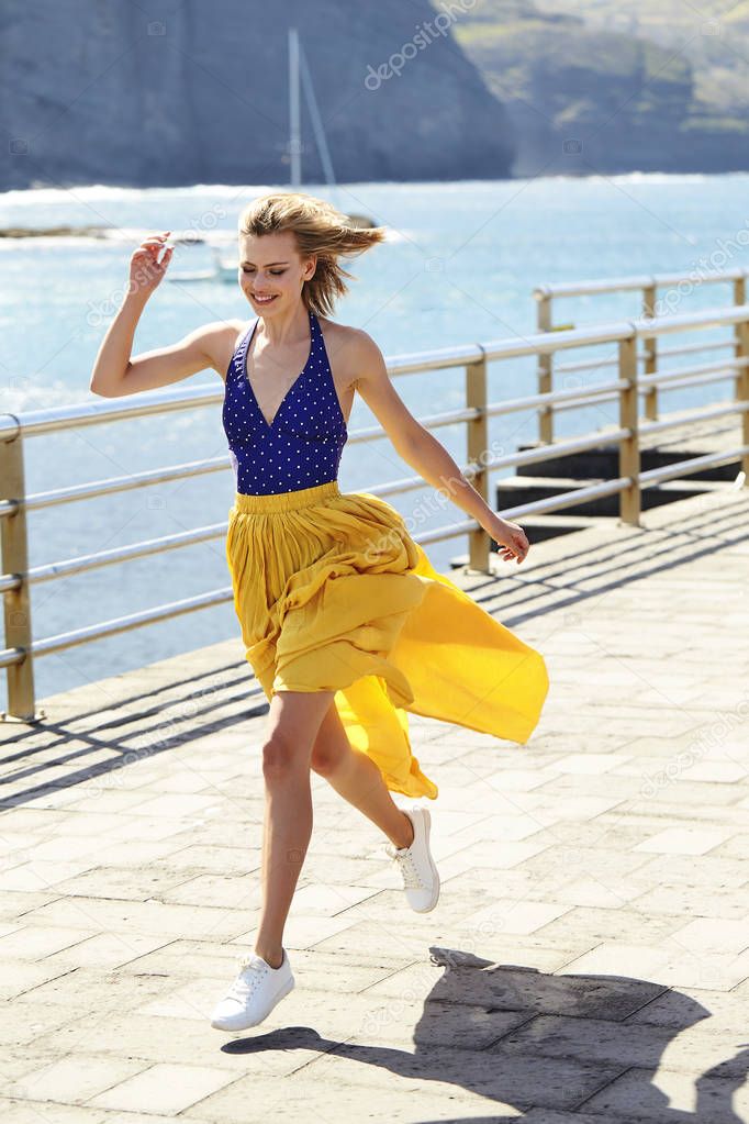 Carefree girl running on pier in sunlight, smiling