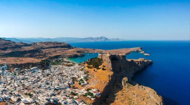 Aerial birds eye view drone photo of village Lindos, Rhodes island, Dodecanese, Greece. Sunset panorama with castle, Mediterranean sea coast. Famous tourist destination in South Europe. clipart