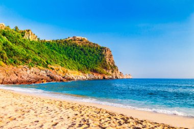 Kleopatra beach Alanya Yarımadası'nda, Antalya bölgesinde, Türkiye'nin yeşil taşlar ile deniz kıyısında. Güzel güneşli manzara ile turizm için temiz su ve kum. Uçurumdaki Alanya Kalesi