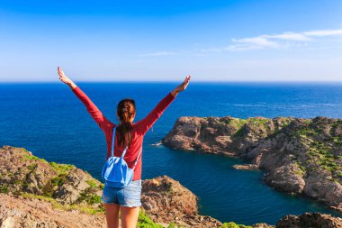 Cap de Creus, doğal park sırt çantası ile turist kadın. İspanya'nın doğu noktası, Girona eyaleti, Katalonya. Costa Brava ünlü turistik yer. Mavi gökyüzü ve bulutlar ile güneşli yaz günü