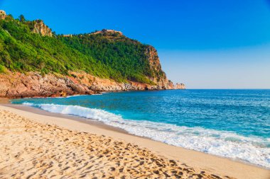 Kleopatra beach Alanya Yarımadası'nda, Antalya bölgesinde, Türkiye'nin yeşil taşlar ile deniz kıyısında. Güzel güneşli manzara ile turizm için temiz su ve kum. Uçurumdaki Alanya Kalesi