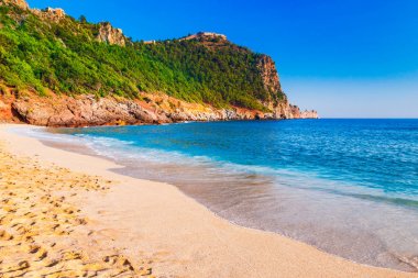 Kleopatra beach Alanya Yarımadası'nda, Antalya bölgesinde, Türkiye'nin yeşil taşlar ile deniz kıyısında. Güzel güneşli manzara ile turizm için temiz su ve kum. Uçurumdaki Alanya Kalesi