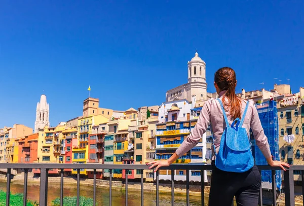 観光客の女性は ジローナ カタルーニャ スペインのカラフルな赤と黄色の家と橋の川オニヤールに見ます 風光明媚な古代の町 有名な観光地の目的地は 休日や休暇のための完璧な場所 — ストック写真