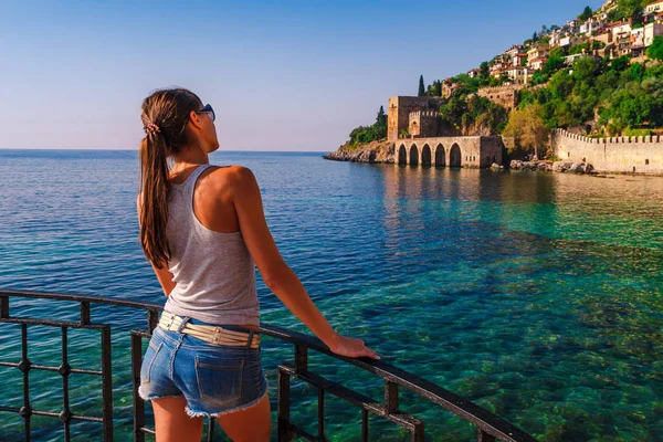 Mujer joven mira en el antiguo astillero de la torre Kizil Kule en la península de Alanya, distrito de Antalya, Turquía, Asia. Famoso destino turístico altas montañas. Parte del antiguo castillo antiguo. Verano brillante día — Foto de Stock