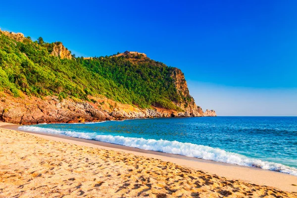 Kleopatra beach Alanya Yarımadası'nda, Antalya bölgesinde, Türkiye'nin yeşil taşlar ile deniz kıyısında. Güzel güneşli manzara ile turizm için temiz su ve kum. Uçurumdaki Alanya Kalesi
