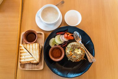 Tavuk çorbası, salatalı pilav ve ahşap masada acı sos..