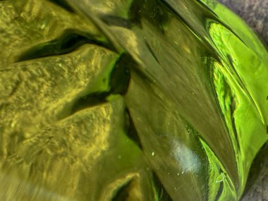 Dalgalı yüzeyi olan yeşil bir nesne. Nesne camdan yapılmış ve o bir vazo.