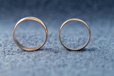 Kumaş mavisi arka planda iki altın alyans, bulanık önplan ve arka plan