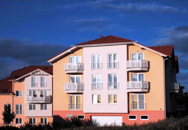 Yeni inşa edilmiş apartman binaları. Güneşli bir arka plan ve renkli aile evleri..