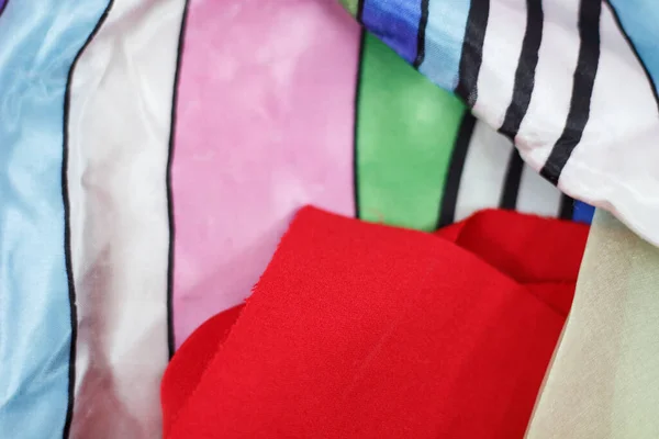Pile of different colored clothes, closeup. Colorful background for fashion theme