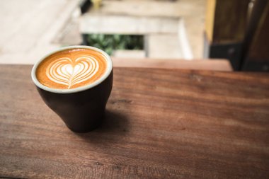 Kalp şekli latte sanatı ile siyah kahve bardağı yakın yukarı