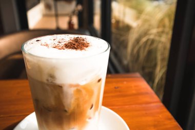 Yakın yukarı çikolata tozu ve süt köpük ile buzlu kahve cam