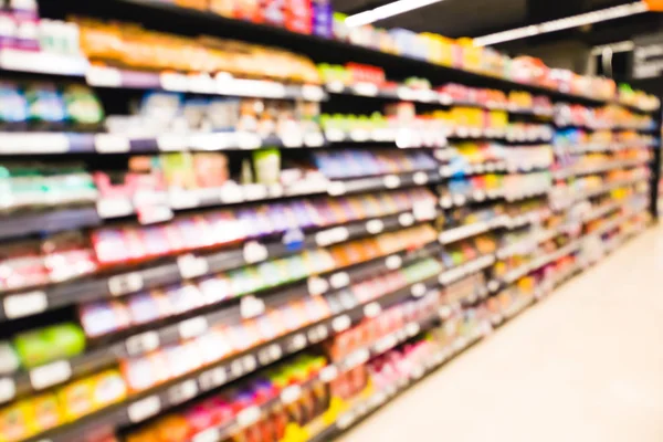 Desenfoque pasillo del supermercado con bocadillos, dulces, papas fritas, galletas, galletas saladas, goma de mascar en el fondo del estante — Foto de Stock