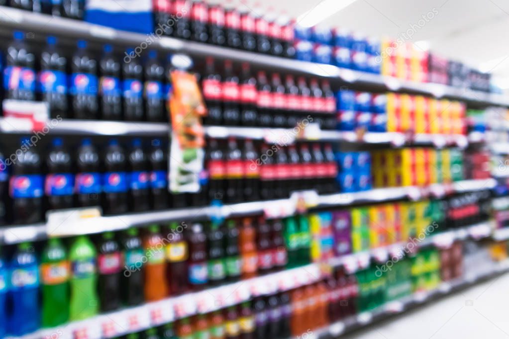 Blurred variety of soft drinks on shelves at grocery store supermarket