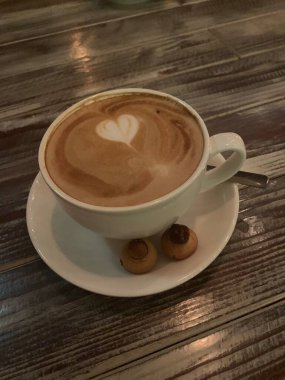 Masanın üzerinde bir fincan kahve. Kahve fincanındaki çizim.