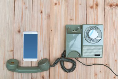 Retro döner telefon veya vintage telefon kablosu ve yeni cep telefonu ile veya ahşap masa, kopya alanı ile üstten görünüm, teknoloji ilerleme kavramı akıllı telefon.