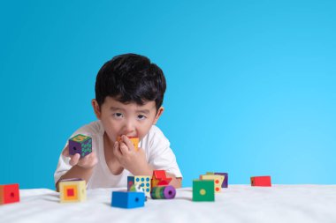 3 yıl eski küçük şirin Asyalı çocuk oynamak oyuncak ya da kare blok bulmaca evde yatakta, yalan blok şekli veya parçalar, eğitim ve sağlıklı kavramı oynayarak öğrenmek.