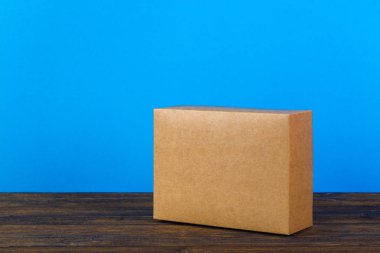 Kopya alanı ile koyu ahşap masa üzerinde sahte için kahverengi karton kutu boş kapandı.